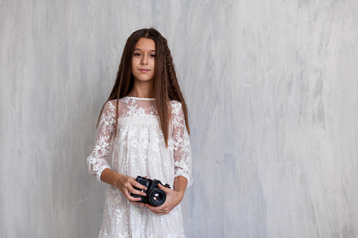 Portrait of a fashionable girl in a white dress with a film camera