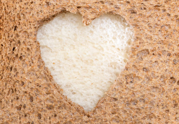 Whole grain sandwich bread slice with heart cut shape and white bread slice inside.