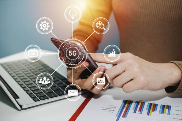 istock 5G. woman hand using digital mobile phone with virtual graphic icon, laptop computer and report on desk at home office, digital marketing, work from home, business finance, network technology concept 1225514638