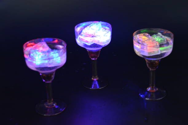 istock Three open champagne glasses with luminous multicolor ice cubes are located on a black matte background. 1225514899