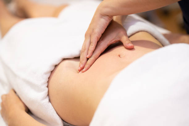frau, die eine bauchmassage in einem physiotherapiezentrum erhält. - abdomen women massaging human hand stock-fotos und bilder