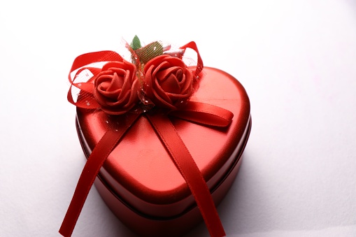 Gift box in heart shape with rose ribbon tied to it