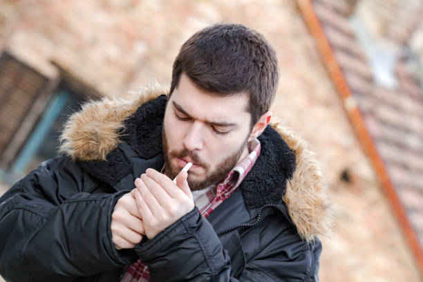 istock Young man with cigarette posing on the street. 1225524560