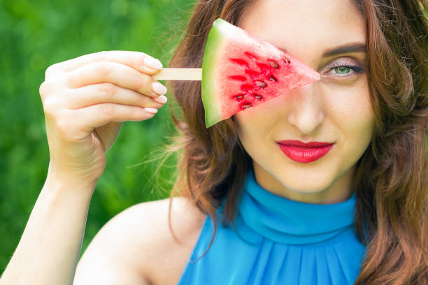 Woman covers eye with watermelon.
