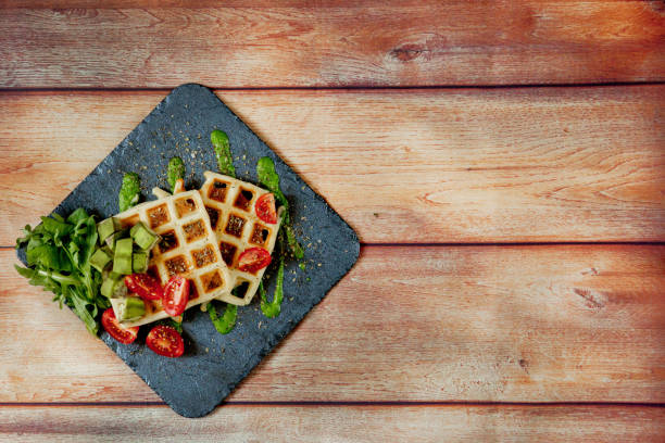istock Fresh baked Belgian waffles with arugula, tomatoes and avocado on black a plate. Savory waffles. Breakfast concept. Healthy breakfast 1225528569