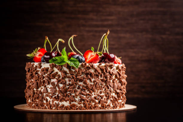 istock Chocolate sponge cake with white cream and berries, strawberries, cherries and mint. Cake cutaway on cinnamon background. copy space 1225530101