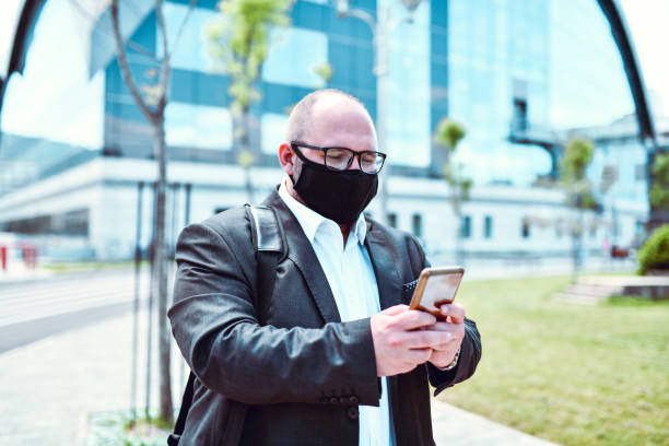 Male Businessman With Medical Mask Having Video Conference Outside Male Businessman With Medical Mask Having Video Conference Outside chief of staff stock pictures, royalty-free photos & images