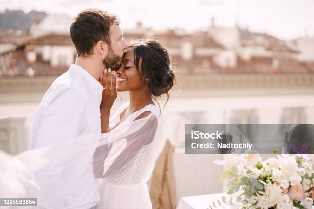 Destination Fineart Wedding In Florence Italy Caucasian Groom And Africanamerican Bride Cuddling On A Rooftop In Sunset Sunlight Multiracial Wedding Couple Stock Photo - Download Image Now