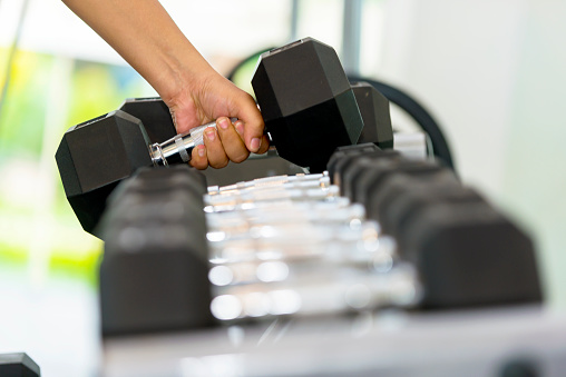 Man hand taking dumbbell on a rack in the gym