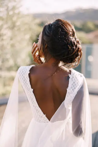 Destination fine-art wedding in Florence, Italy. The African-American bride stands with her back, in a white dress with a large neckline against the backdrop of Florence's urban landscape.