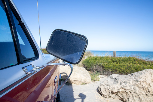 Close-up of the side of a red truck and the view looking out onto the beach.
