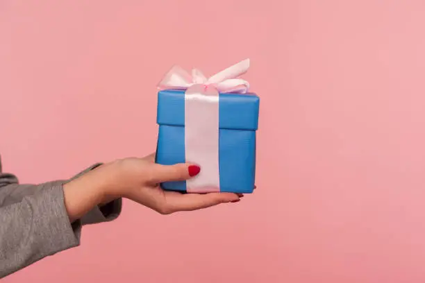 Photo of Closeup hand holding elegant blue gift box with ribbon, romantic surprise for Valentine's day, Christmas holidays