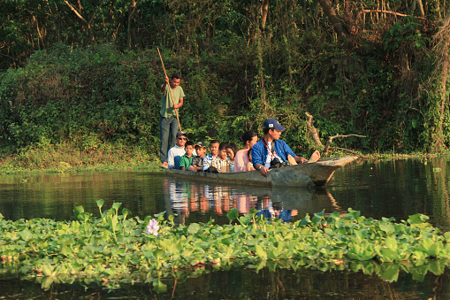 Chitwan, Nepal - March 31, 2014: people on a boat trip at the river in Chitwan national park in Nepal to watch animals like crocodiles, birds and fishes.