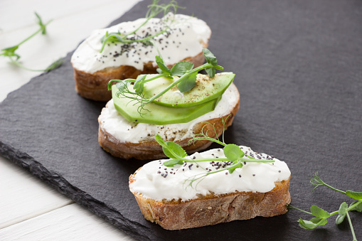 Healthy sandwiches with avocado , cream cheese and micro green. Vegan sandwiches, vegan food, healthy eating. Template with space for text , black  and white background