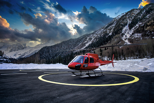 Red helicopter on the helipad at sunset.