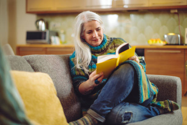 mujer madura en casa - women book mature adult reading fotografías e imágenes de stock