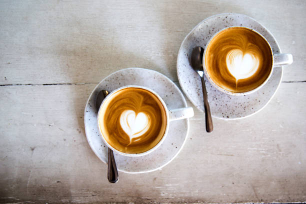 istock Two Cups of hot cappuccino on white wooden table background. 1225548308