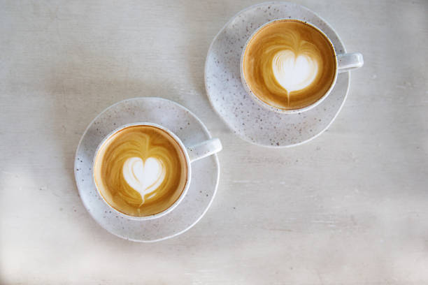 istock Two Cups of hot cappuccino on white wooden table background. 1225548335