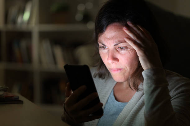 preoccupied adult woman reading on phone at night at home - waiting telephone on the phone anxiety imagens e fotografias de stock