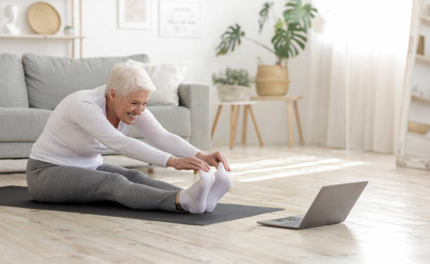Active Senior Woman Doing Warming Stretching Exercises In Front Of Laptop Home Sport. Active Senior Woman Doing Warming Stretching Exercises In Front Of Laptop, Training With Online Tutorials pilates photos stock pictures, royalty-free photos & images