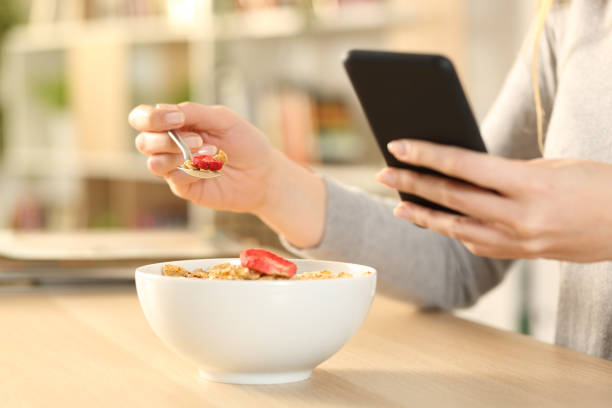 istock Woman hands eating cereal bowl checking phone at home 1225552378