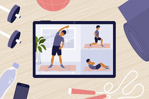 Online workout classes on tablet with man on screen doing exercises