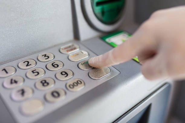 istock Wearing Gloves While Using ATM To Protect From Covid-19 Infection. Hand in rubber glove clicks on buttons of ATM, enters password, protection against coronavirus in public place 1225554660