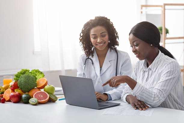 아프리카 여성 영양사 및 환자 노트북 화면을 보고 - women black fruit healthcare and medicine 뉴스 사진 이미지