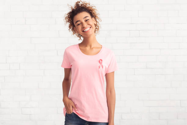 ragazza volontaria per il cancro al seno sorridente in posa sul muro di mattoni bianchi - t shirt shirt pink blank foto e immagini stock