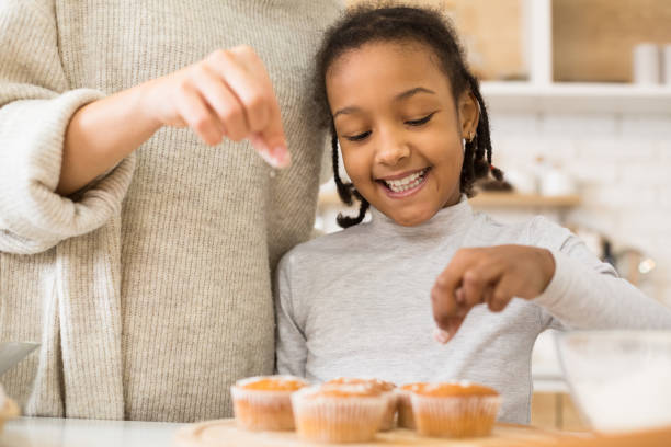 istock Mother and daughter decorating cupcakes together at home 1225556151