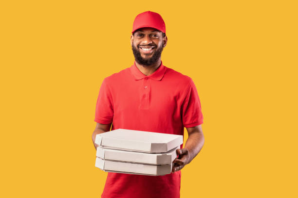 istock Pizzeria Courier Man Delivering Pizza Standing On Yellow Studio Background 1225556454