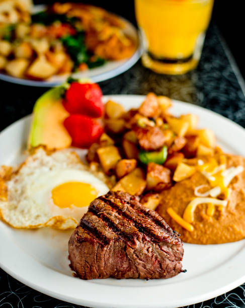 istock Steak and eggs. Classic American breakfast or brunch favorite. Filet & sunny side up eggs served with potato hash and fresh fruit. 1225556537