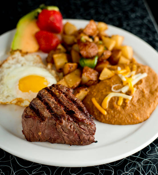 istock Steak and eggs. Classic American breakfast or brunch favorite. Filet & sunny side up eggs served with potato hash and fresh fruit. 1225556559