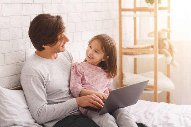 istock Father and daughter using laptop in bedroom 1225557839