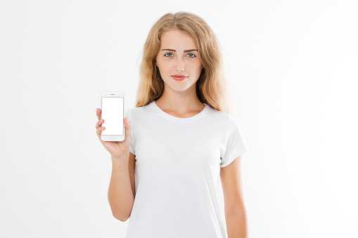 Portrait of a happy cheery teenage girl dressed in white t-shirt holding blank screen mobile phone.
