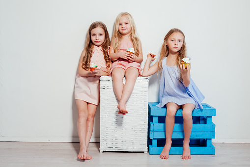 three little girls girlfriend eat sweet cake with cream cupcake