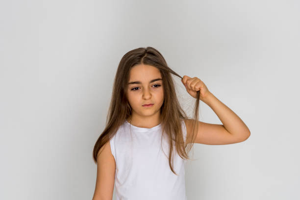 istock Little beautiful sad girl pulls her hair isolated on white background 1225559578