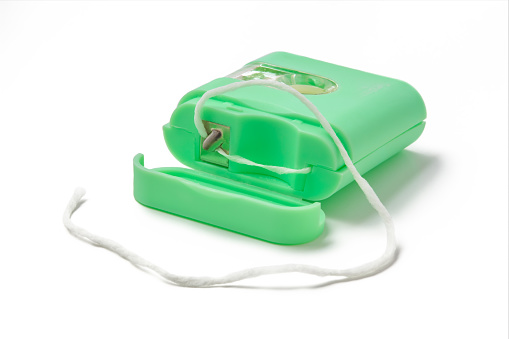 Green dental floss container on white background.