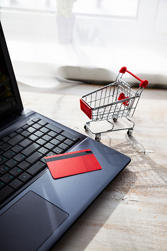 Laptop with a credit card and shopping cart. Online shopping.