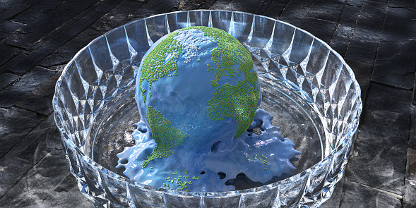 A conceptual image of a scoop of blue ice scream with green and brown sparkles arranged in the shape of countries on planet earth. The ice cream sits in a glass bowl on a dark slate tile floor, and is melting as a metaphor for climate change.