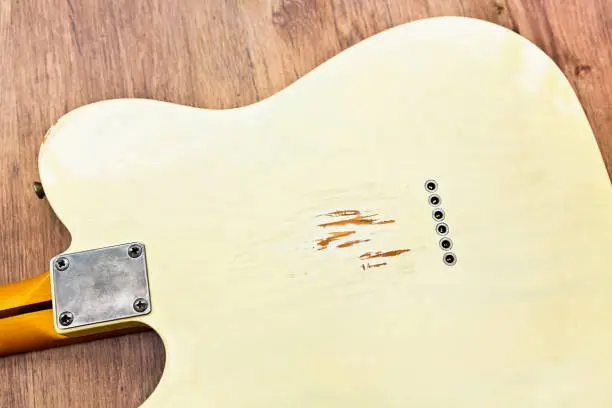 Reverse of an electric guitar with damage caused by belt buckle during playing.