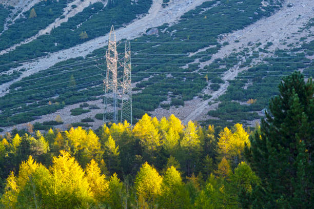High voltage electrified pylon in the mountains. In the background the Marmolada massif in the Belluno Dolomites, Veneto, Italy, Europe, a popular destination for skiers, hikers and snowshoes.