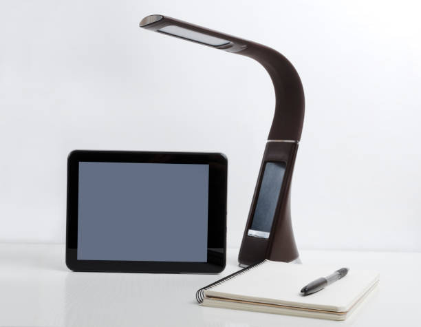 istock Tablet pc, lamp and notebook on the white table against white wall.Concept of home office.Empty space 1225565732