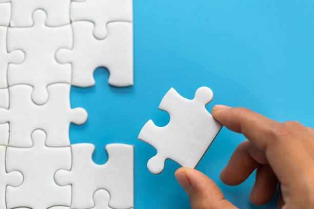 jigsaw connection between white  jigsaw puzzles, jigsaw puzzle in the hand of a businessman,  business team assembling jigsaw puzzle. - jigsaw puzzle solution one person people imagens e fotografias de stock