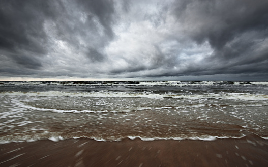Storm clouds above the North sea in winter, long exposure. Dramatic sky, waves and water splashes. Dark seascape. Netherlands
