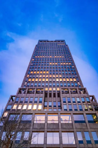 End of day bottom up shot of mostly empty but partially illuminated office building