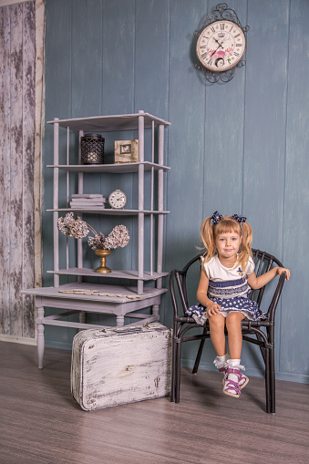 Portrait of a little girl in retro vintage photographic studios.