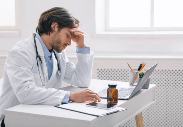 istock Tired male doctor suffering from headache at workplace 1225569459