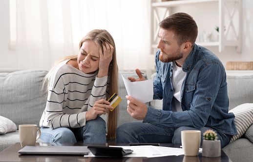 Financial depression. Stressed woman with credit card suffering from her angry husband