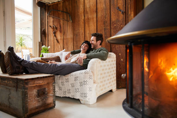 istock Couple laughing and talking while warming up with tea by their fireplace 1225575158